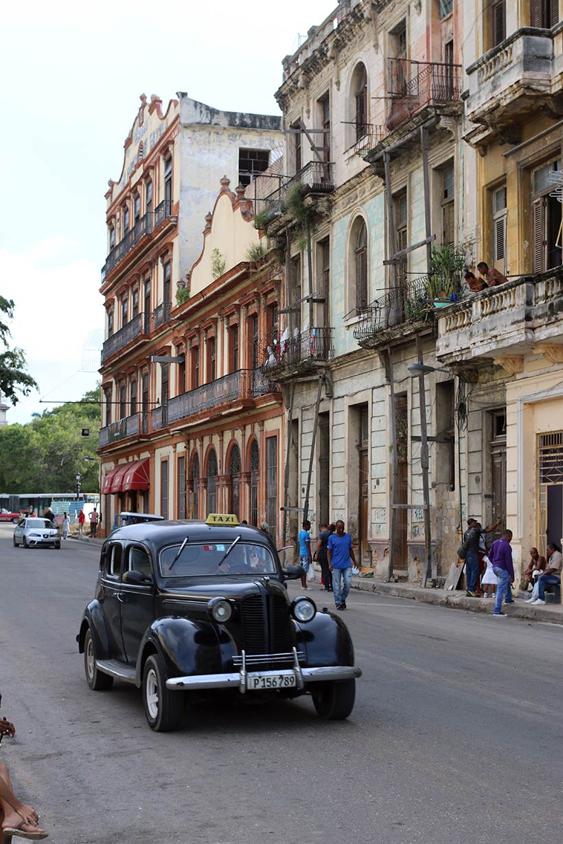 Contraste entre táxi e edifícios antigos na capital de Cuba